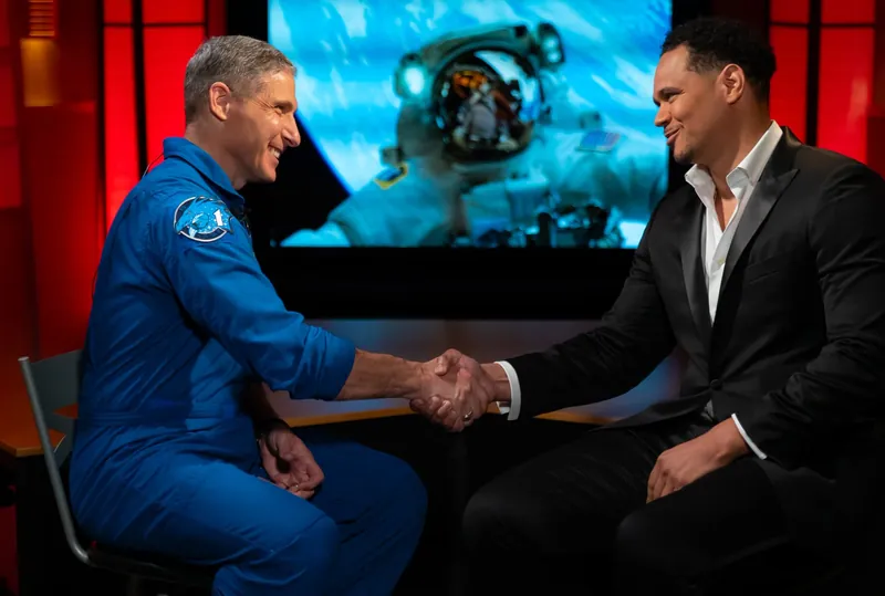 Kiva Geiger shaking hands with NASA astronaut Mike Hopkins in a television studio