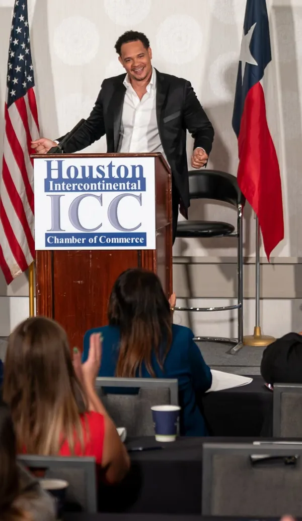 Kiva Geiger smiling at the podium as the audience applauds
